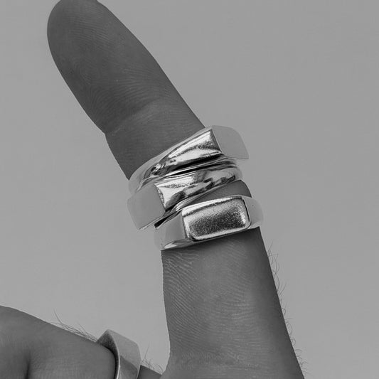 Silver ring on a finger against a gray background