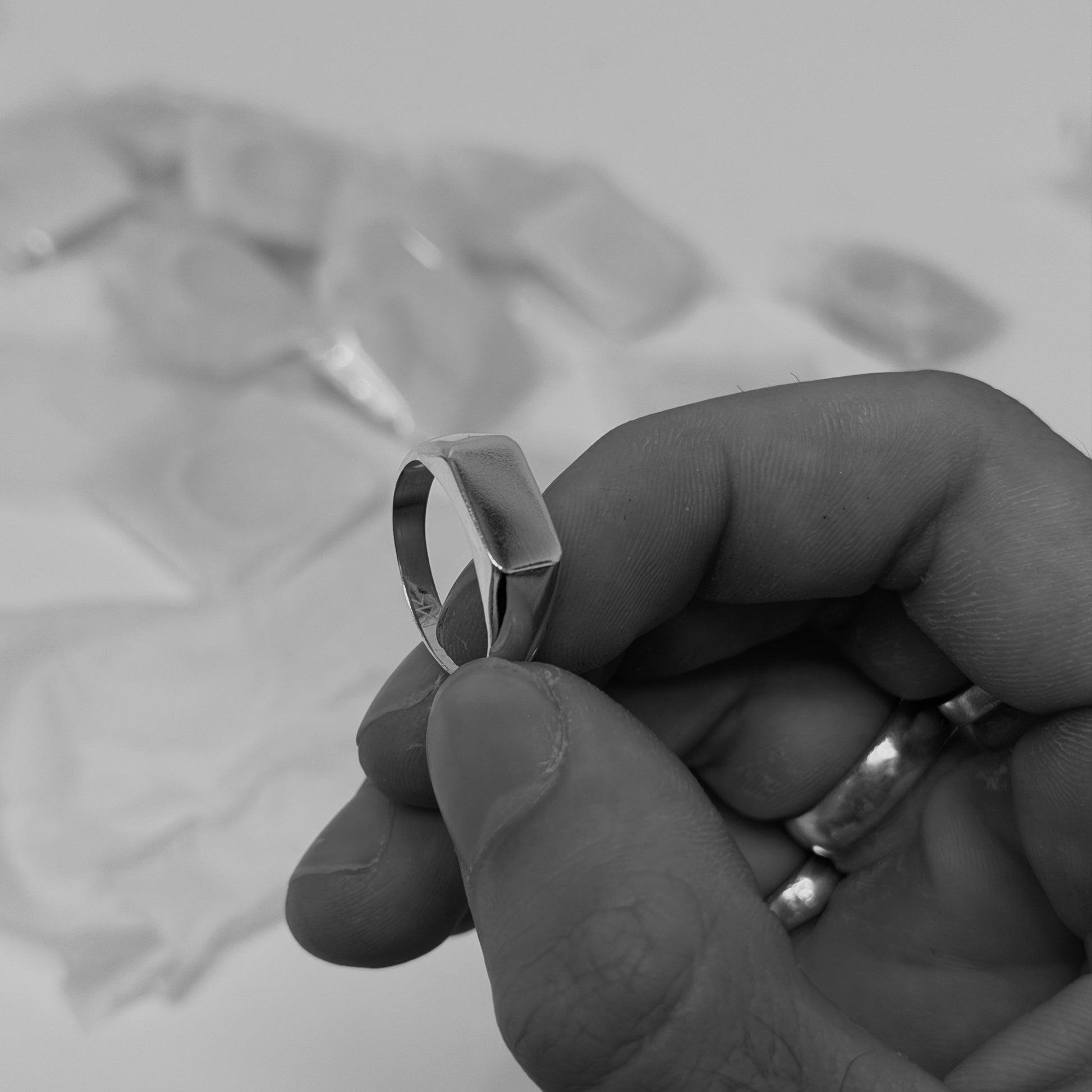 Hand holding a silver ring with a blurred background